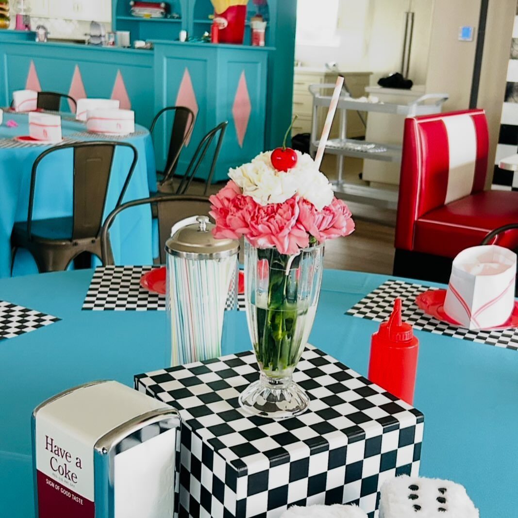 Diner themed table setting with blue cloth and black and white checkered accents