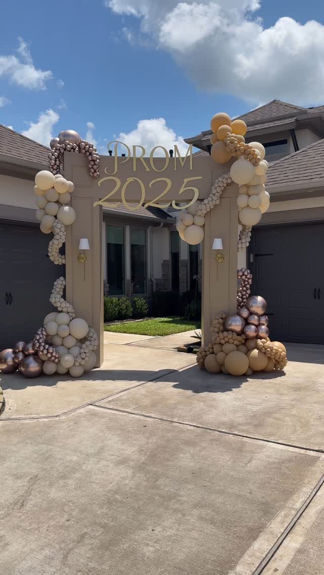 Gold and white balloon arch framing a PROM 2025 sign at an entrance