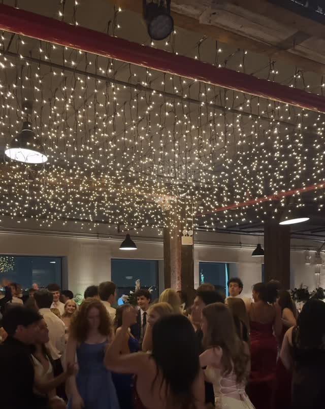 Young people dancing under a ceiling filled with shimmering warm white fairy lights.