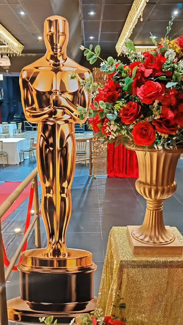 Gold Oscar statue and red roses in a gold vase for prom decorations
