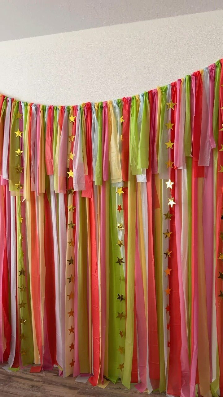Colorful fabric strip backdrop with gold stars for a party photo area.