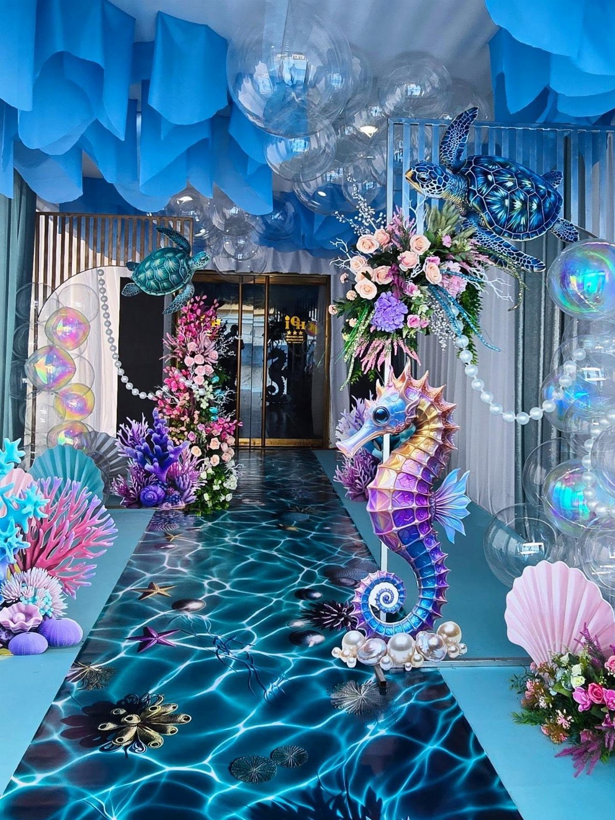 Underwater themed event entrance with blue and turquoise colors, seahorse, and coral decorations.