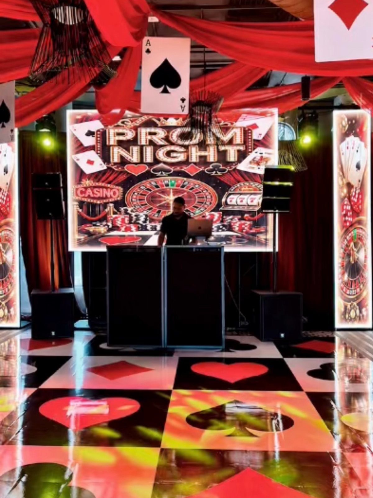 DJ booth and glossy dance floor with red and black playing card symbols