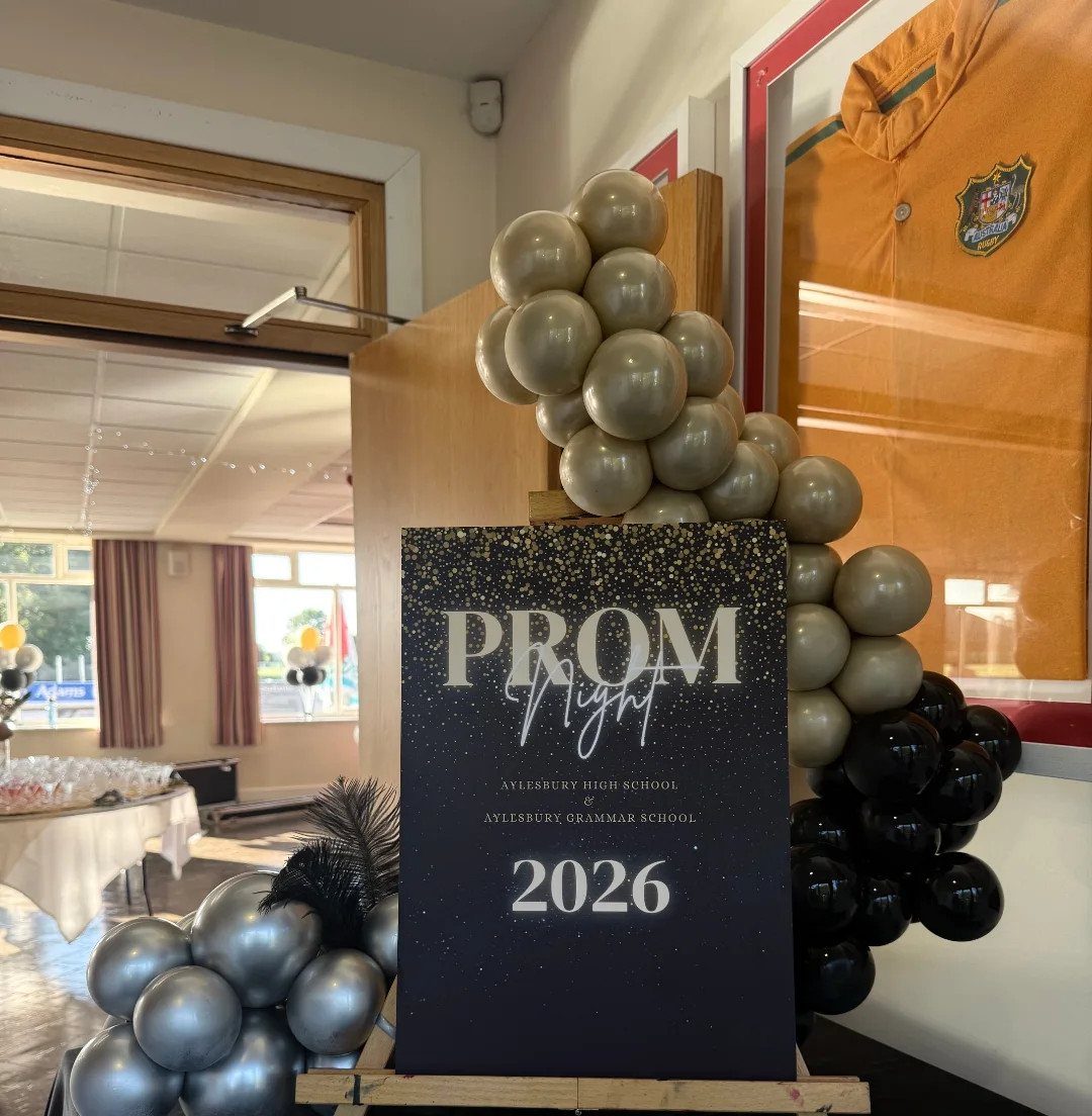 Prom Night 2026 sign framed by gold and black balloon arches in a room.