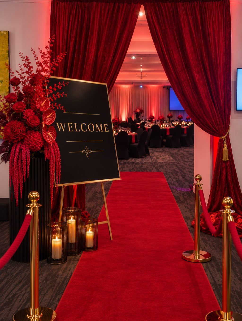 Red carpet entrance with gold stanchions, velvet ropes, and red curtains leading inside.