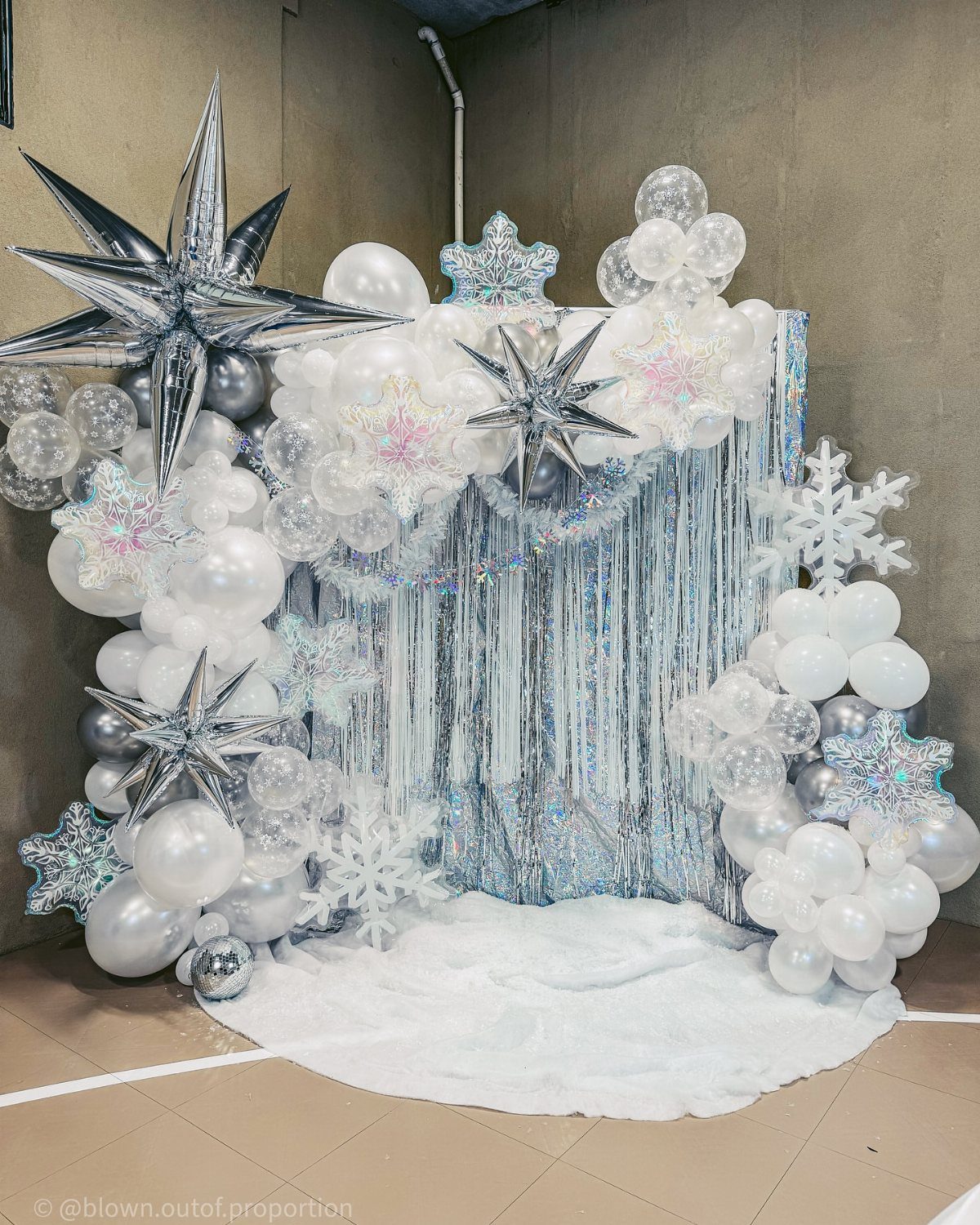 Winter themed backdrop with white balloons, silver stars, and large white snowflakes.