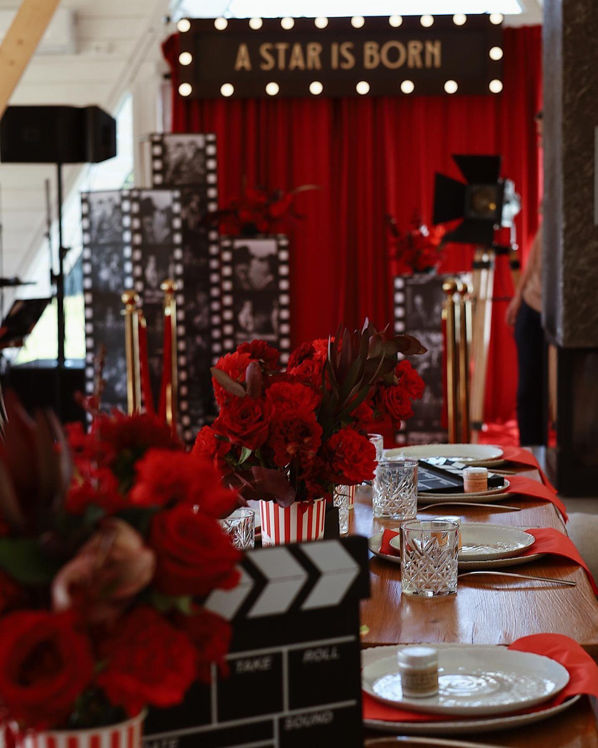 Movie themed party table with red roses, film strips, and a marquee sign.