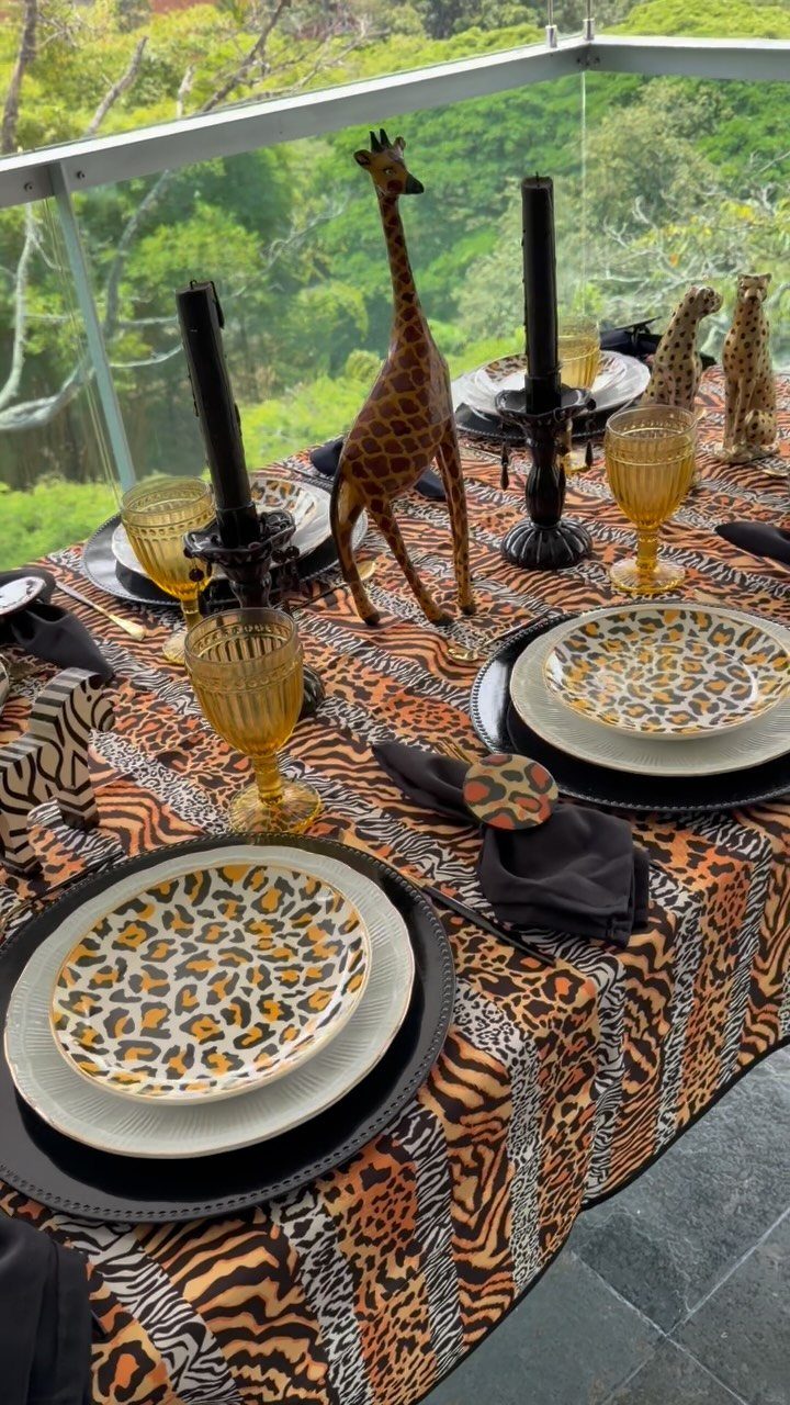 Safari table setting with animal print plates, tiger-print tablecloth, and giraffe figurine.
