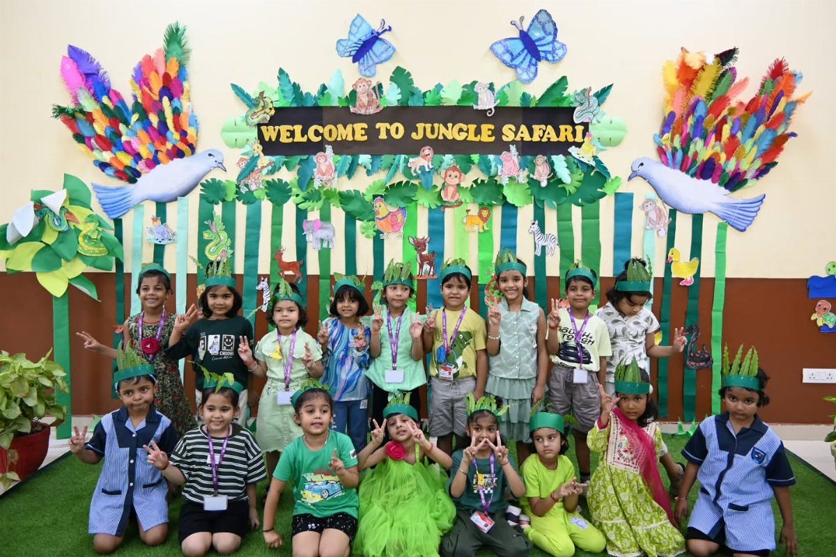 Children in leaf headbands posing before a colorful jungle safari party backdrop.