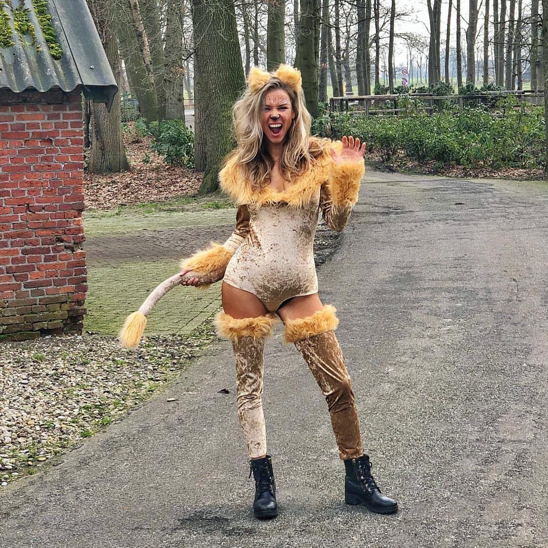 Woman in a tan lion costume with faux fur and boots posing outdoors.