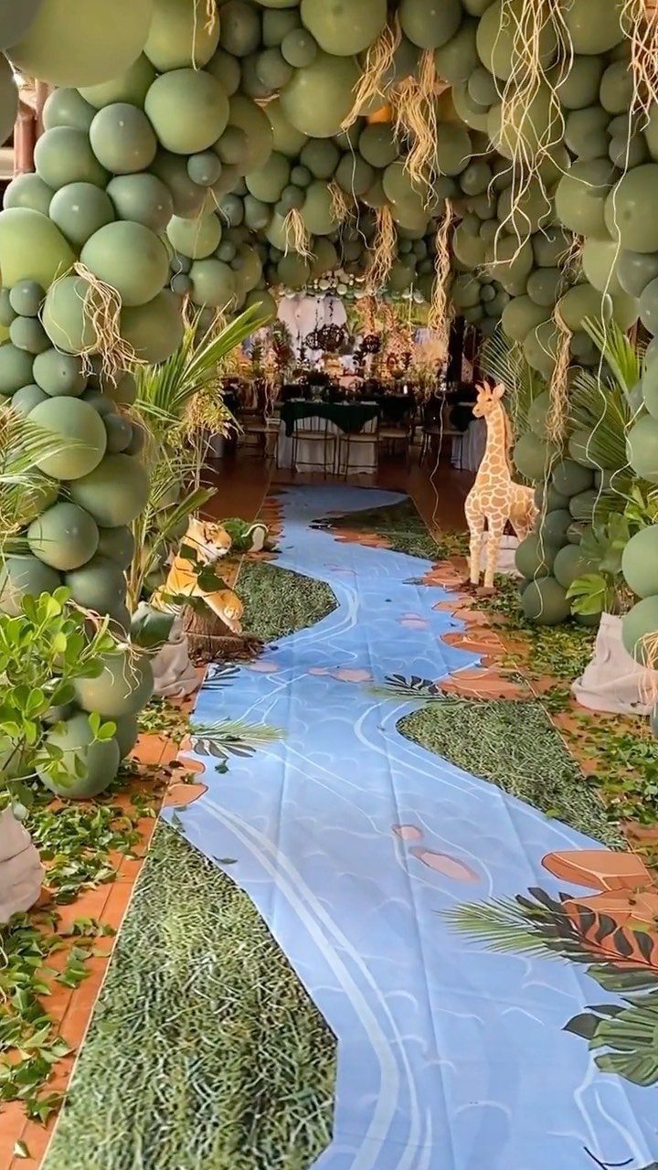 Green balloon arch and river floor runner with giraffe statue for safari party