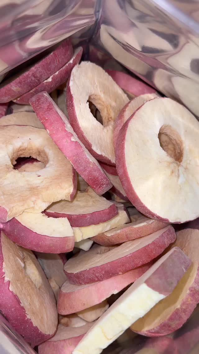 Dried apple rings with red skins stored in a clear plastic bag.