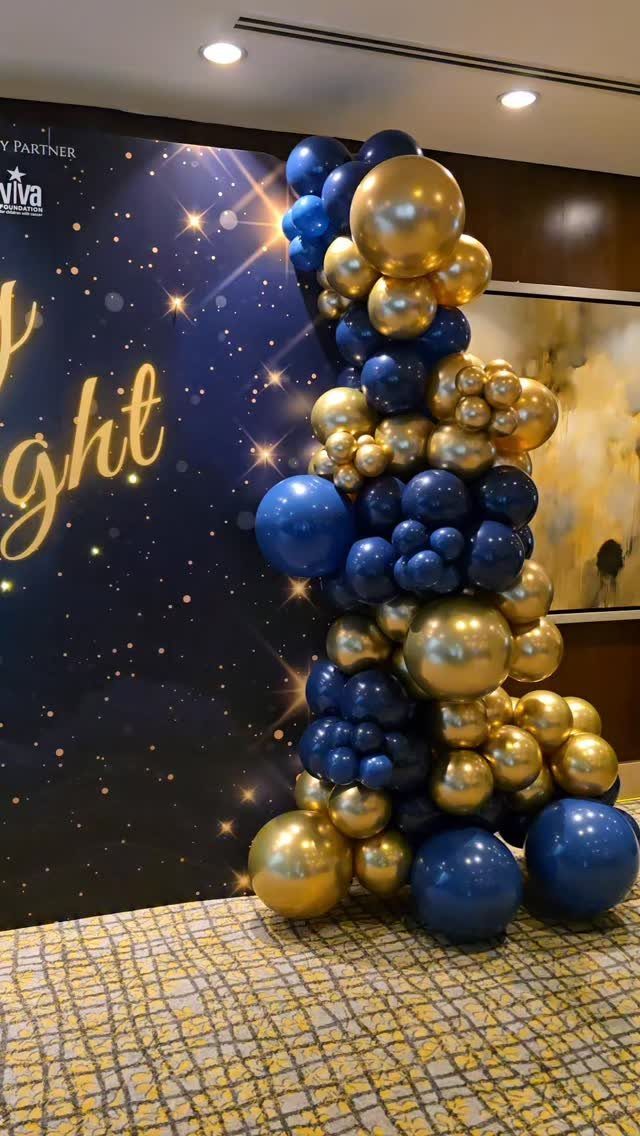 Blue and gold balloon pillar next to a starry night themed backdrop.