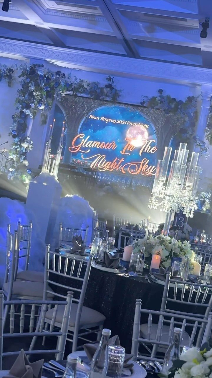 Prom venue with blue lighting, silver chairs, and a starry night backdrop.