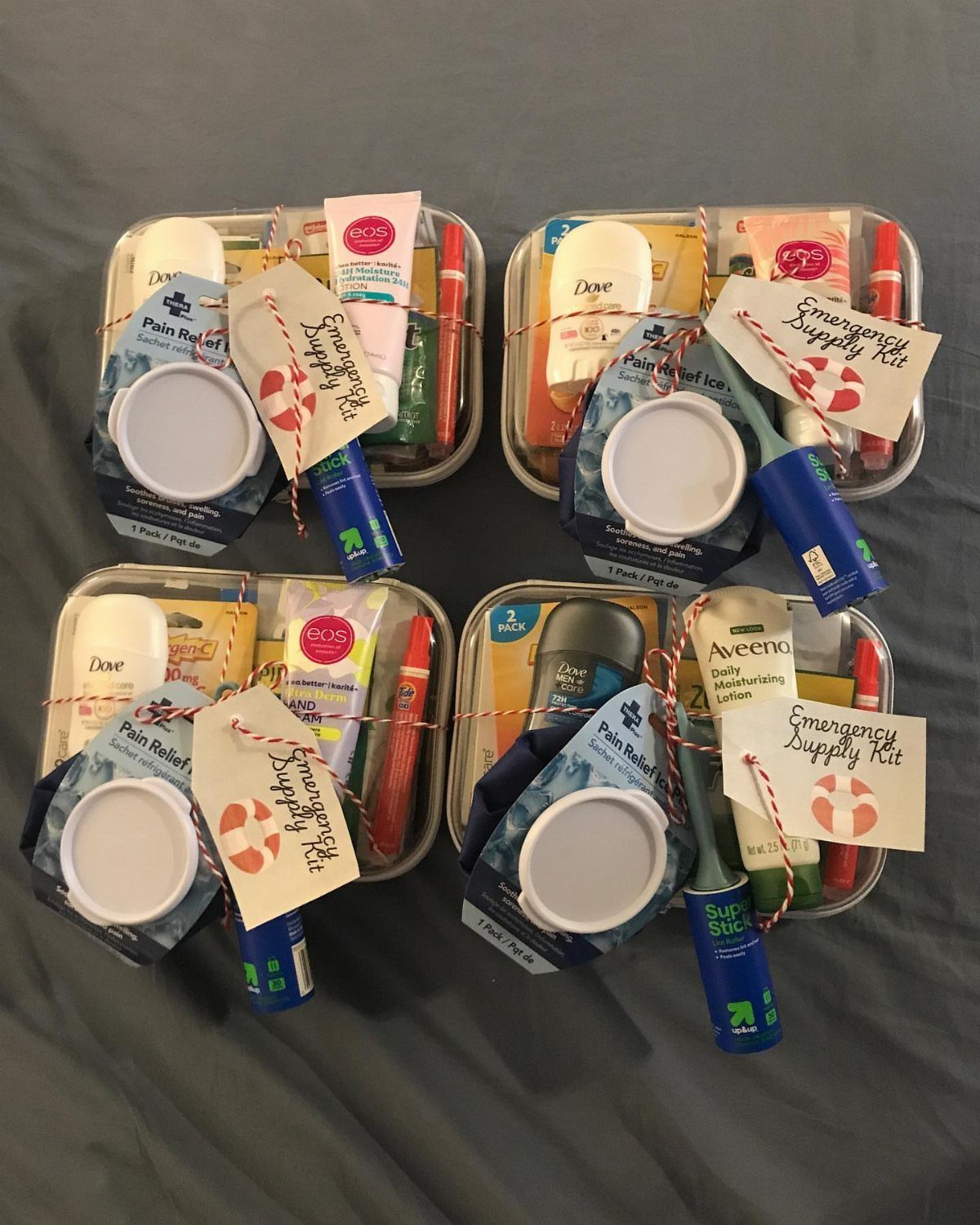 Four emergency supply kits in metal tins containing toiletries and red pens.