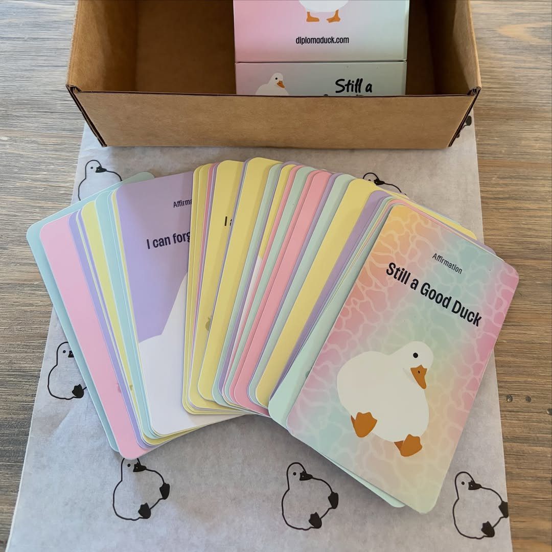 Colorful pastel affirmation cards with a white duck illustration on a patterned surface.