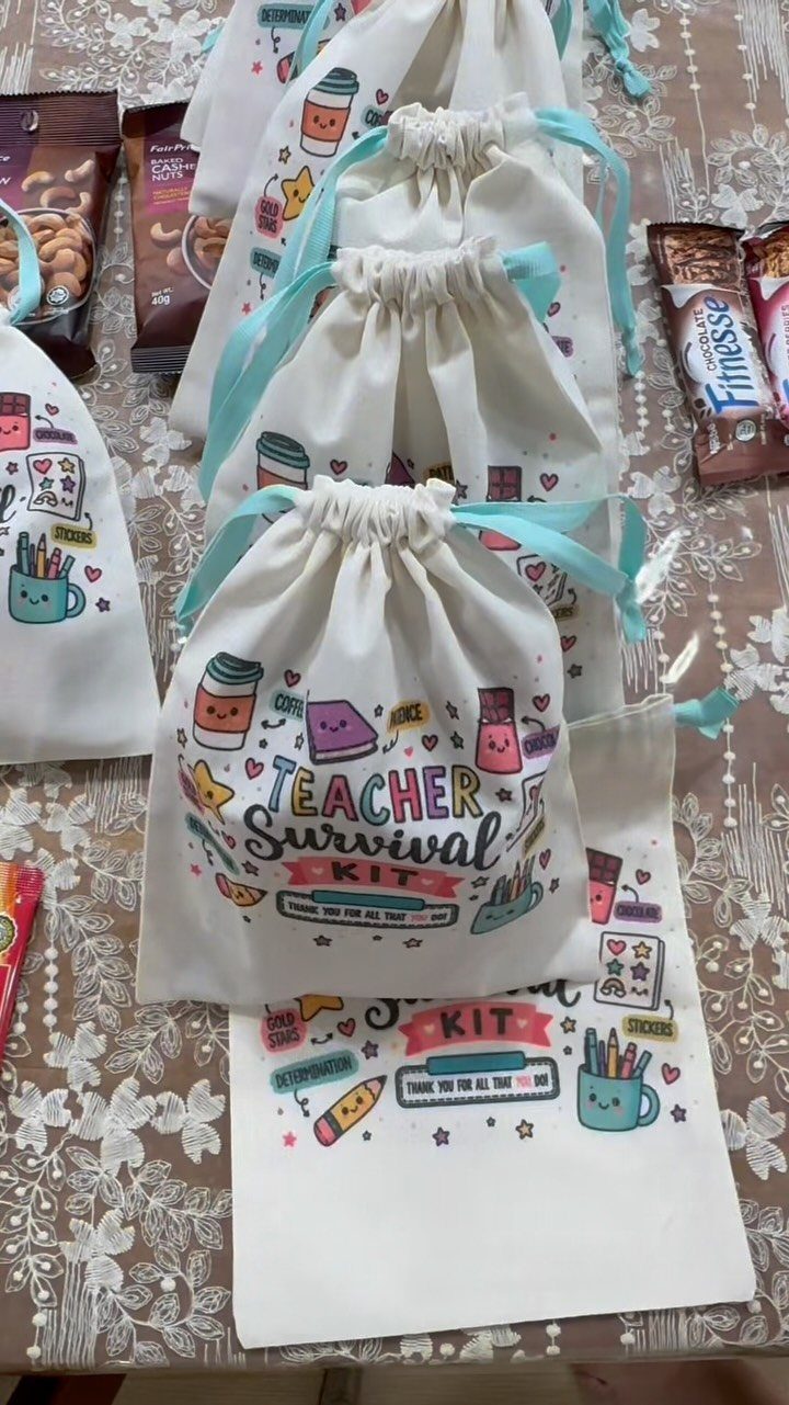 White drawstring bags printed with Teacher Survival Kit and school icons on floral tablecloth