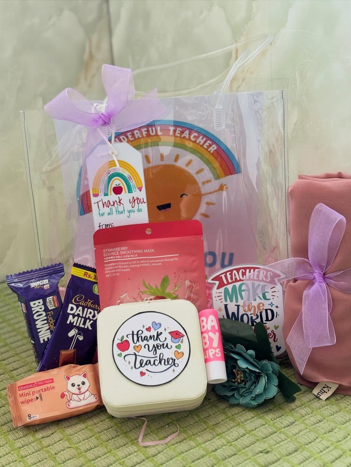 Teacher survival kit with chocolates, a thank you tin, and purple ribbons.
