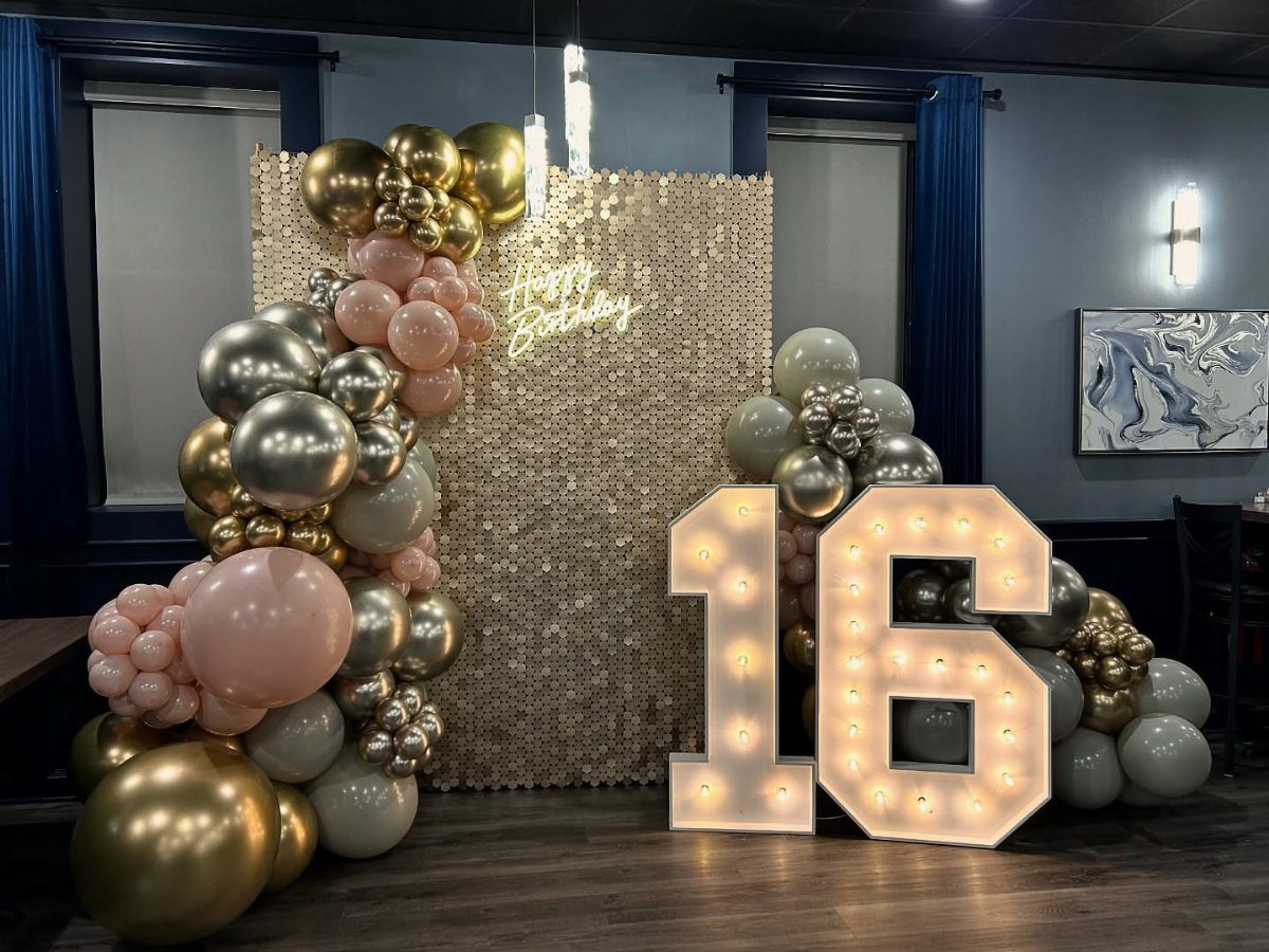 Gold shimmer wall with balloon garland and large illuminated number 16 marquee lights