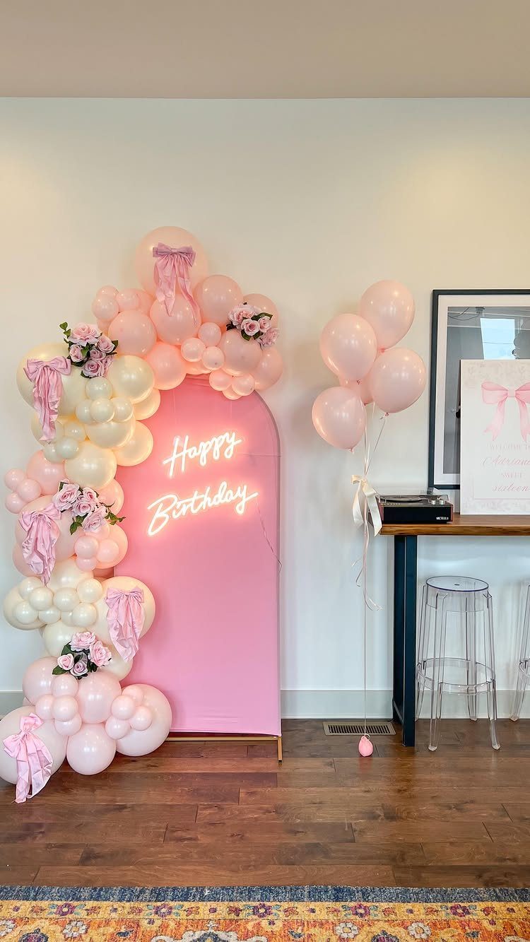 Pink arched backdrop with neon Happy Birthday sign and pink and white balloon garland