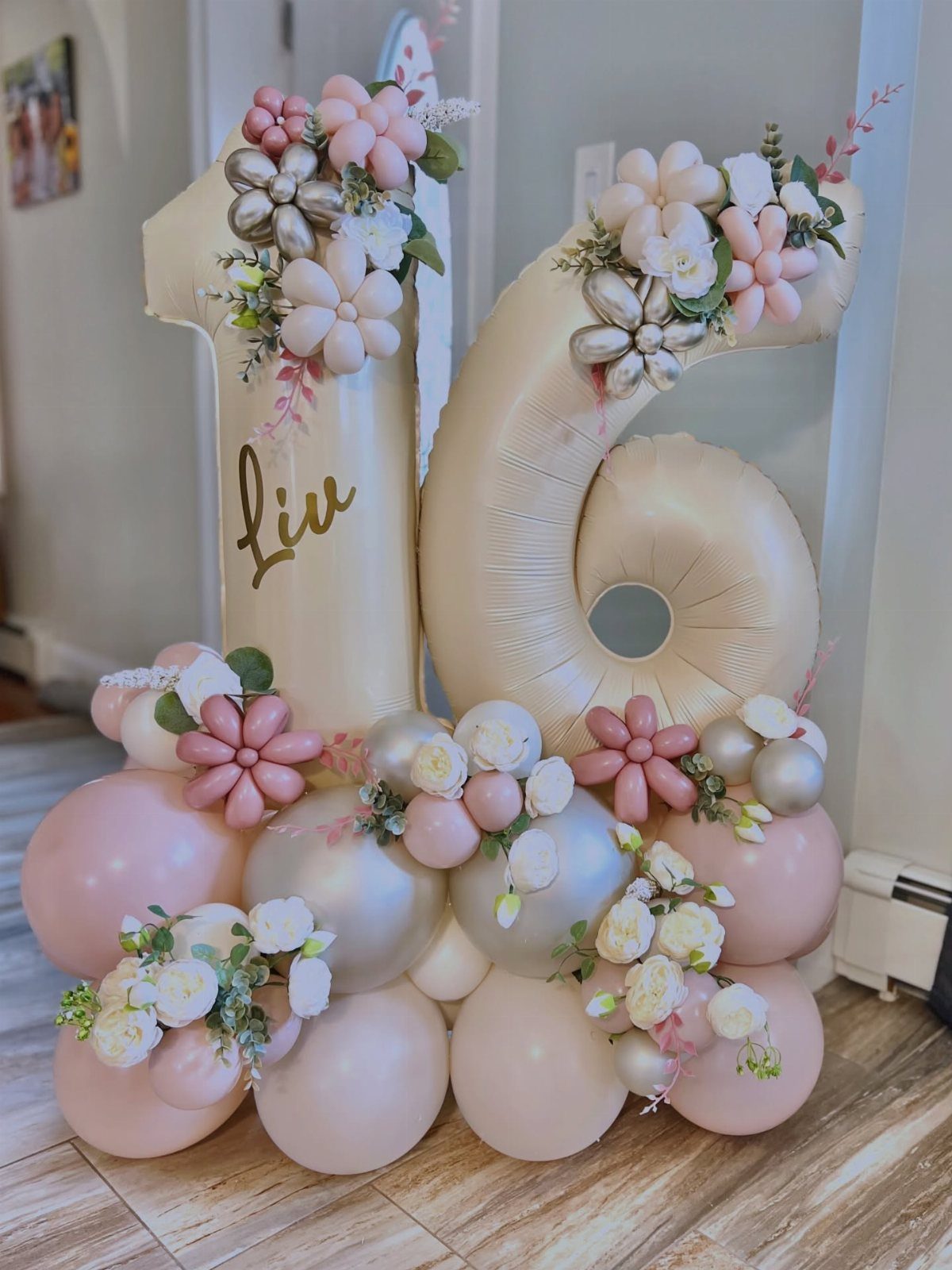Gold foil number 16 balloons decorated with pastel balloon flowers and white roses.