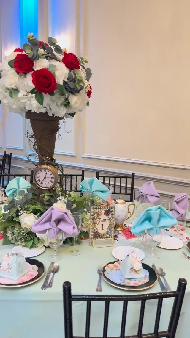 Whimsical tea party table setting with colorful napkins, gold teapot, and floral centerpiece.