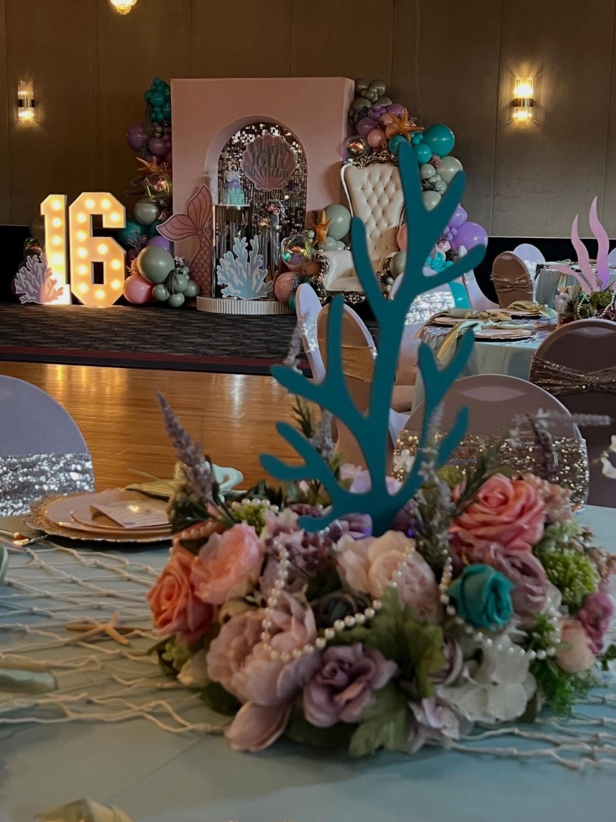 Floral centerpiece with teal coral and pearls for an under the sea party.