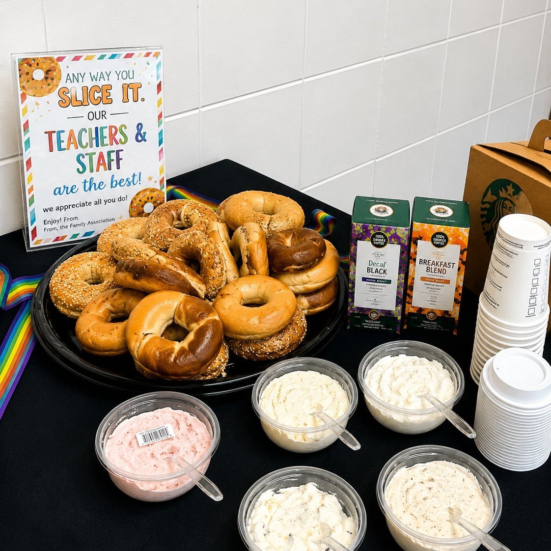 Assorted bagels and cream cheese spreads on a table with a teacher appreciation sign.