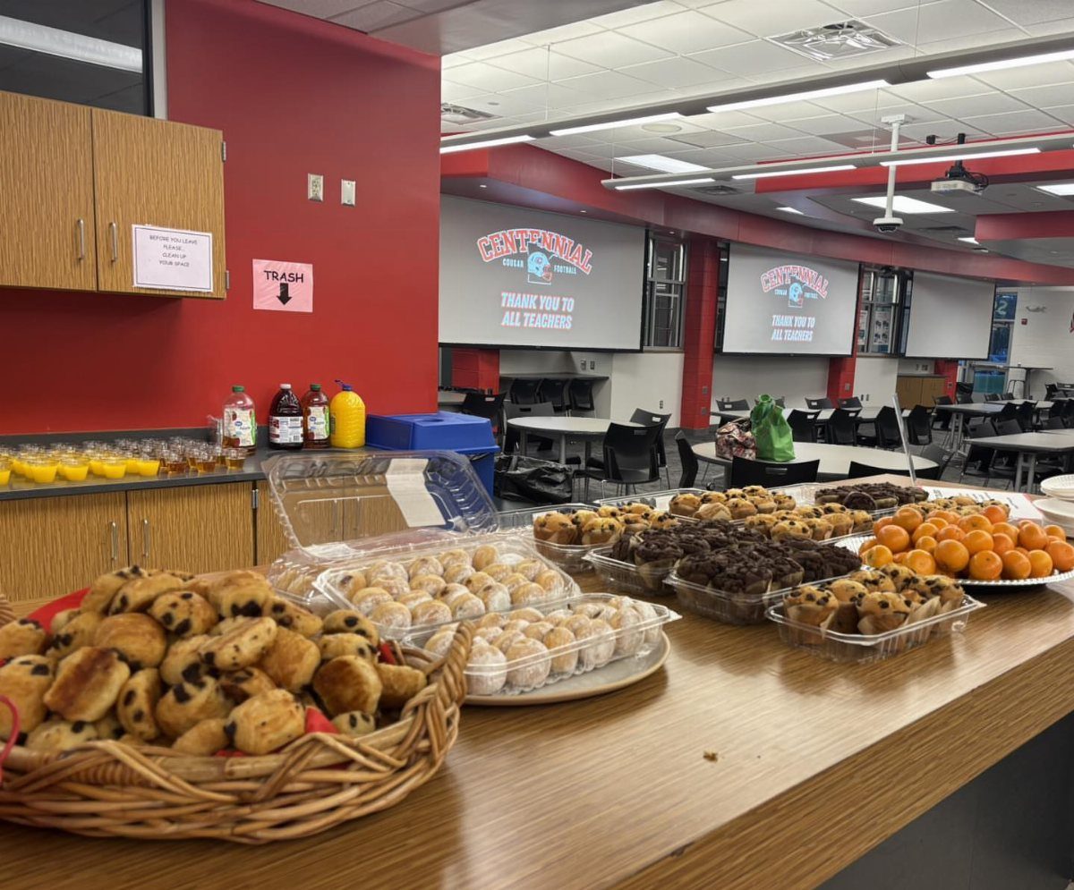 Breakfast spread with mini muffins, powdered donuts, pastries, and clementines on a counter.