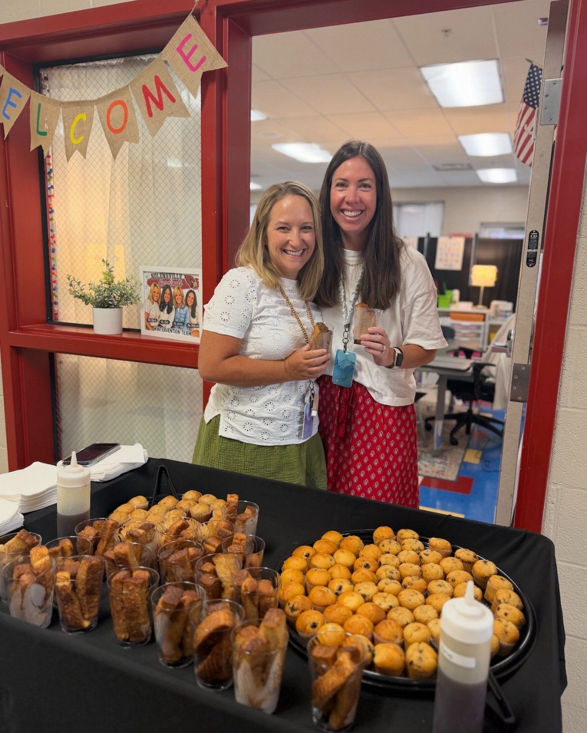 Two women standing behind a breakfast spread of mini french toast and muffins.