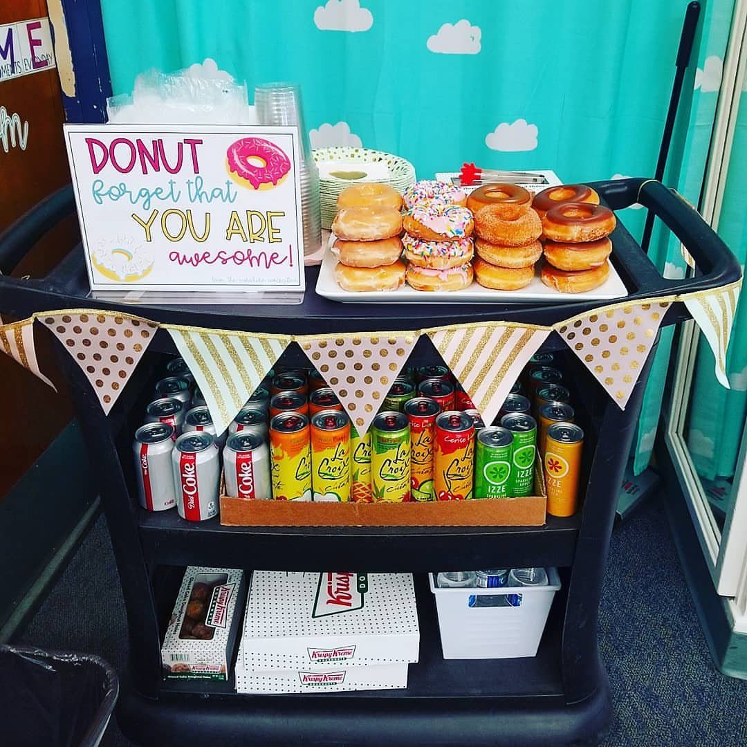 Donuts and canned drinks arranged on a black rolling cart with a decorative sign.