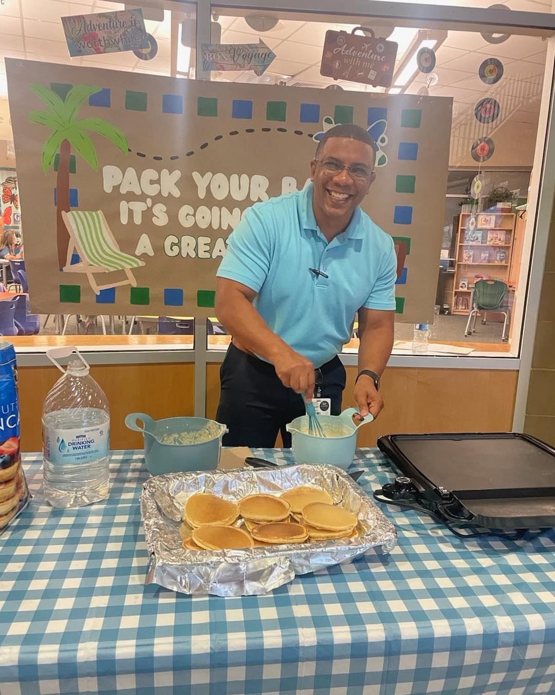 Man cooking pancakes on an electric griddle at a breakfast station event.