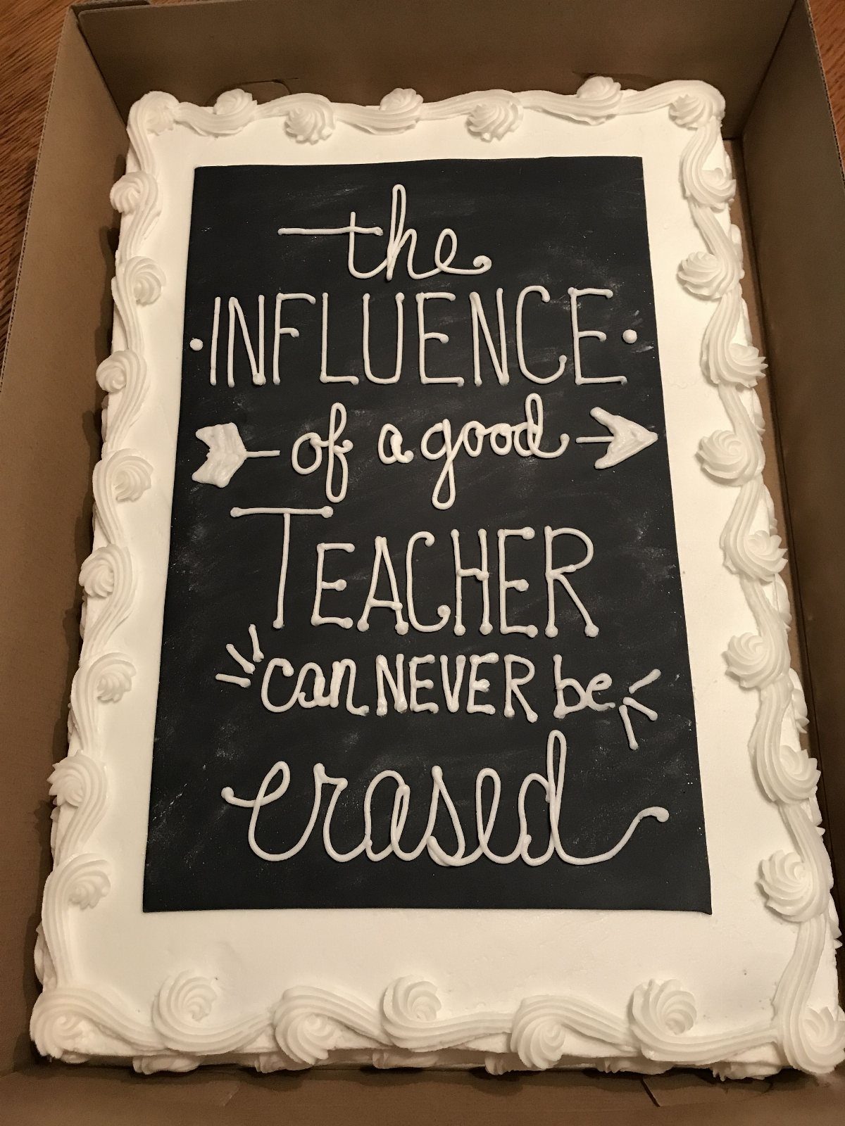 Rectangular chalkboard cake with white frosting border and teacher appreciation message.