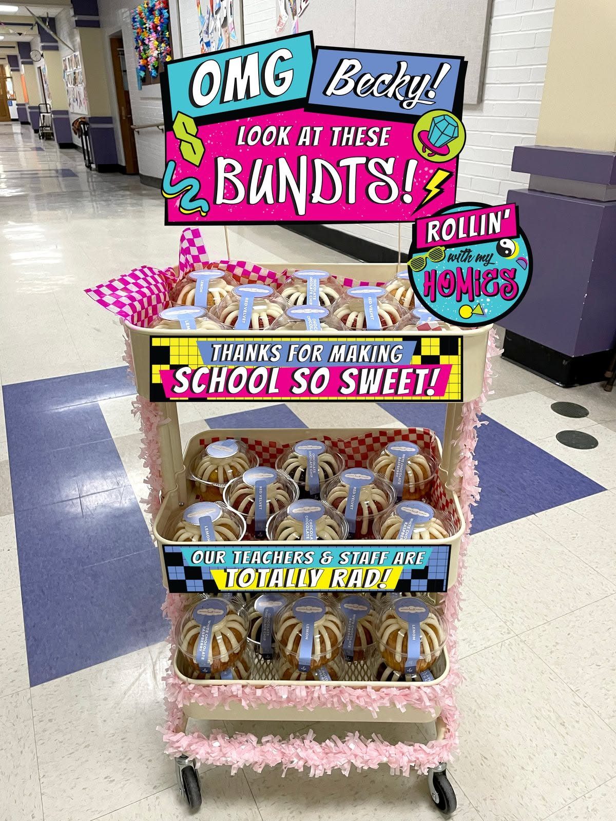 Rolling cart with bundt cakes and neon retro signs for teacher appreciation.