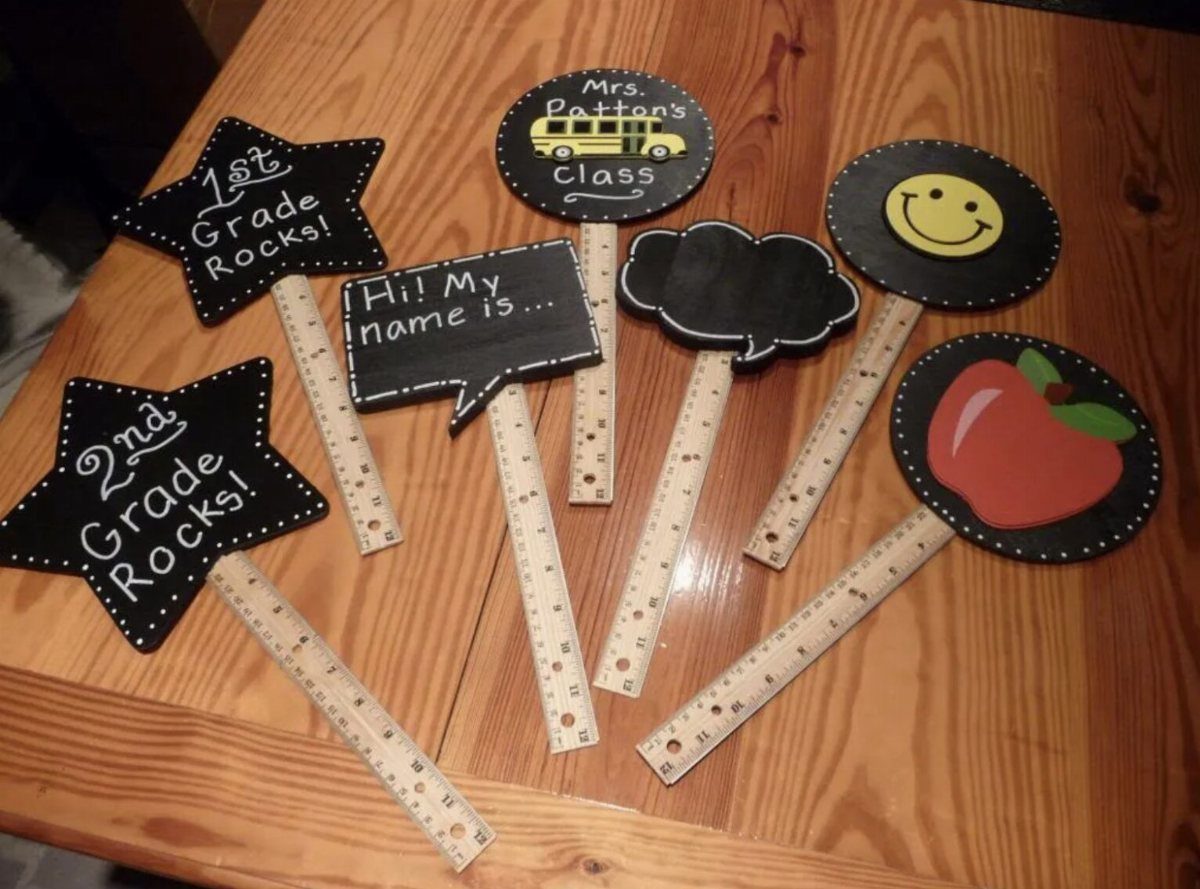 Handheld photo props with school themes and ruler handles on a wooden table.
