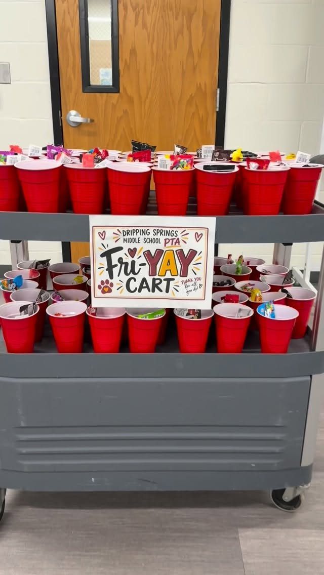 Grey utility cart filled with red buckets of snacks and a Fri-YAY sign.