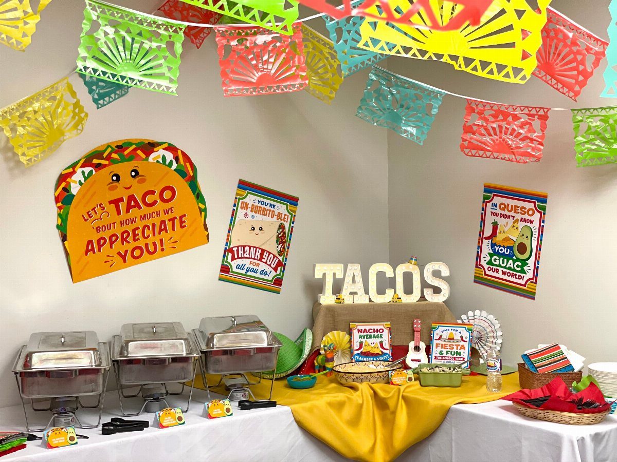 Taco-themed appreciation station with colorful banners, food warmers, and festive signage.