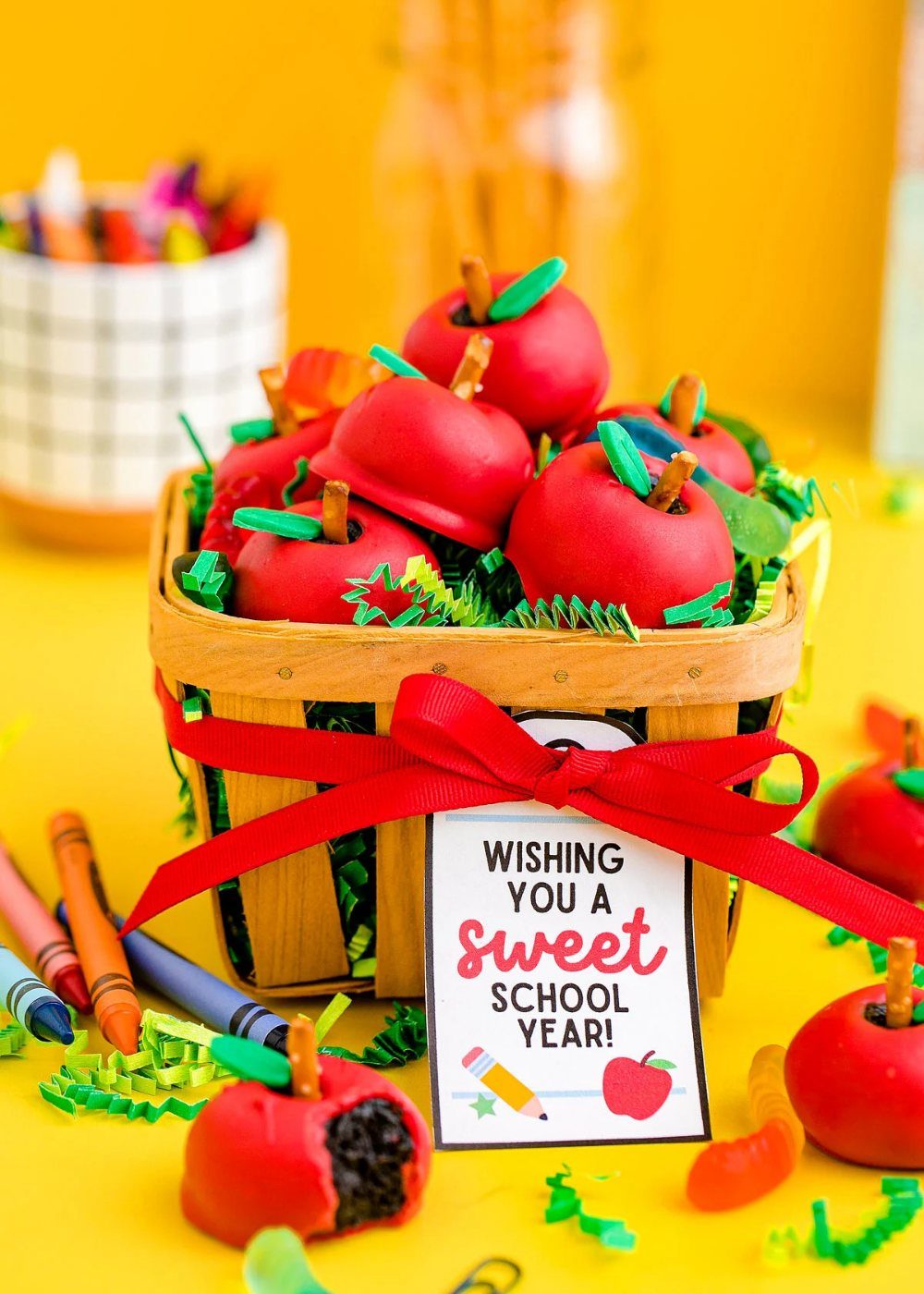 Apple-shaped chocolate cookie balls in a wooden basket with a school-themed gift tag.