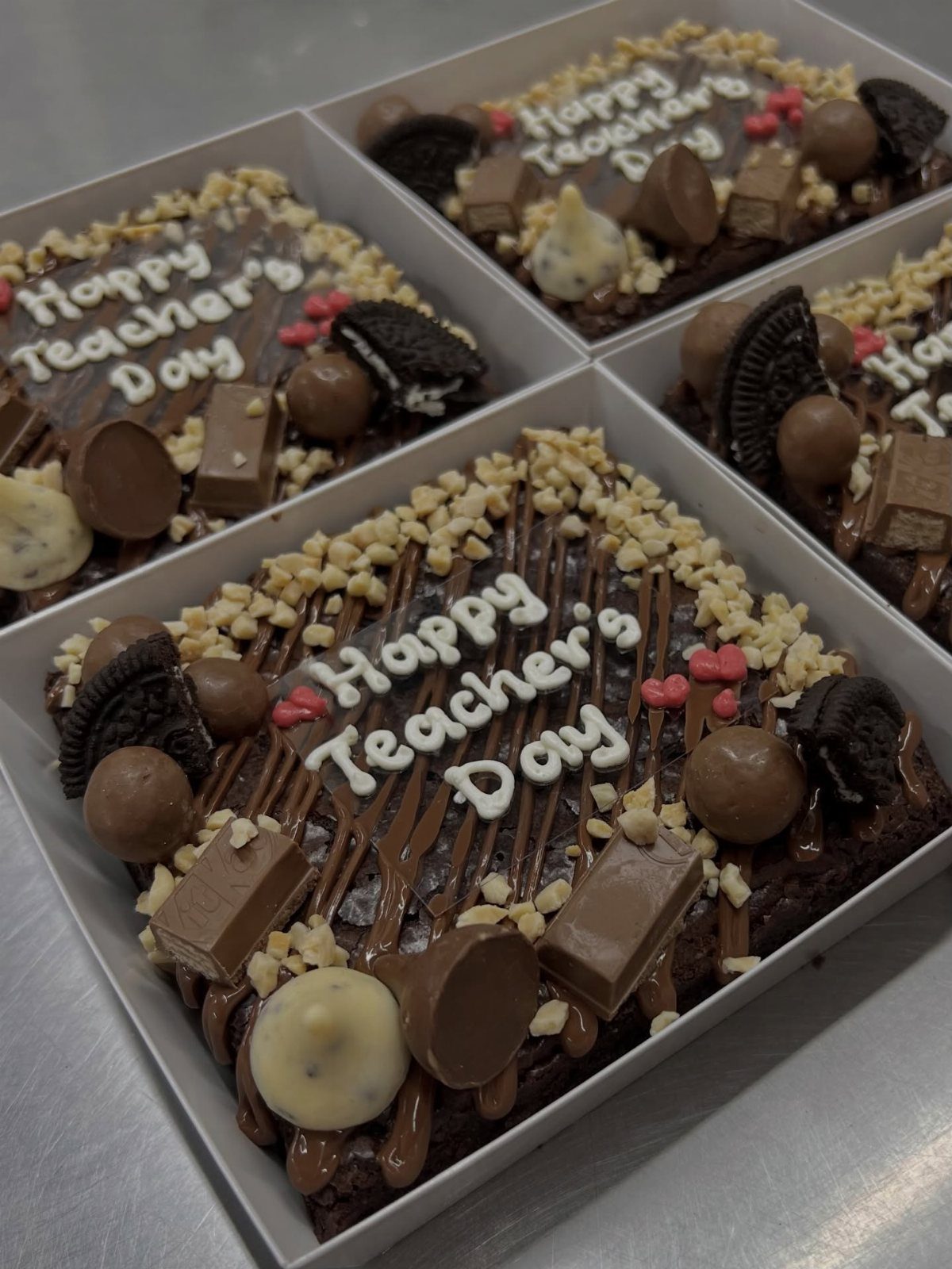 Chocolate brownies topped with nuts and candy, labeled Happy Teacher's Day in icing.