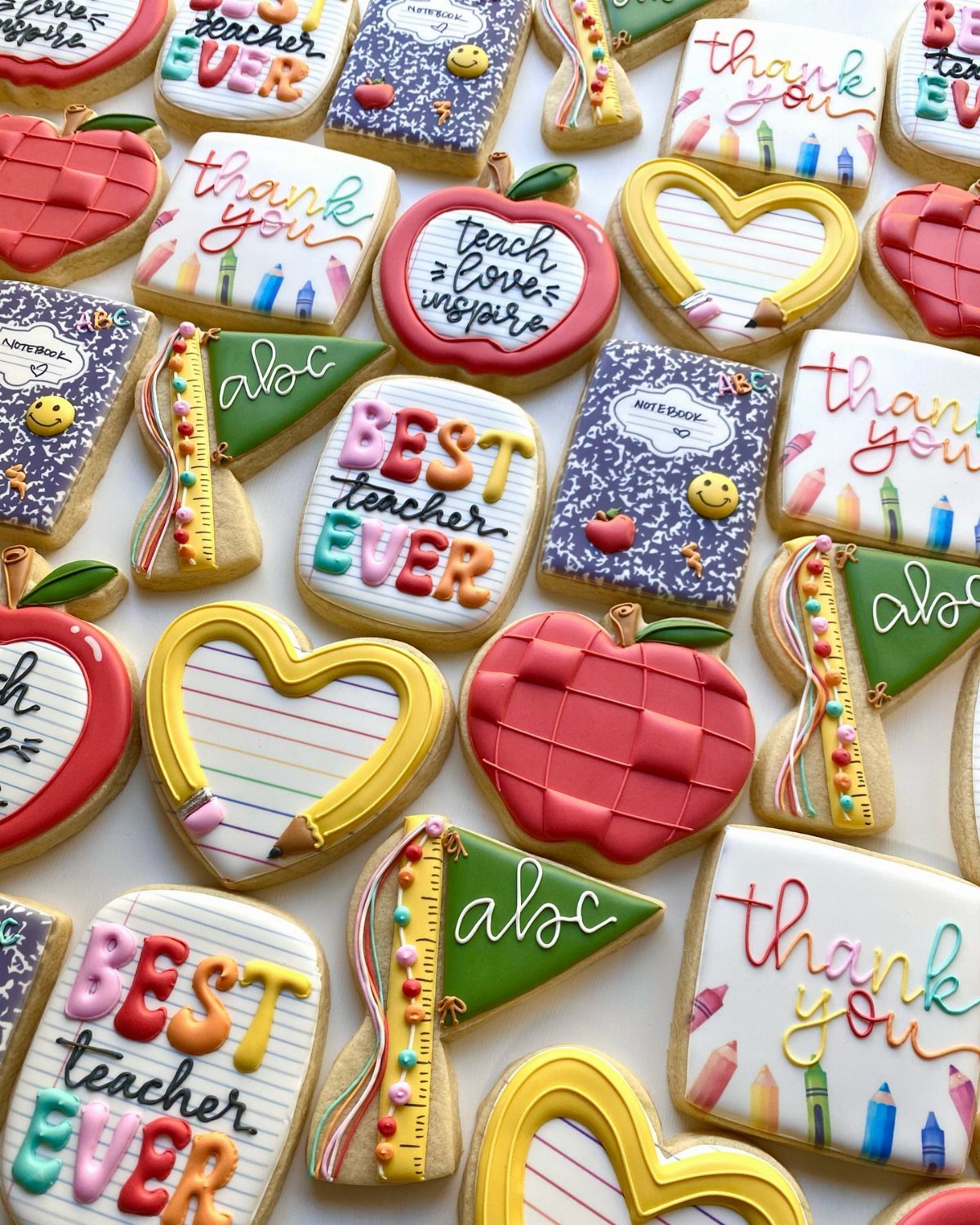Decorated sugar cookies in shapes of apples and notebooks for teacher appreciation.