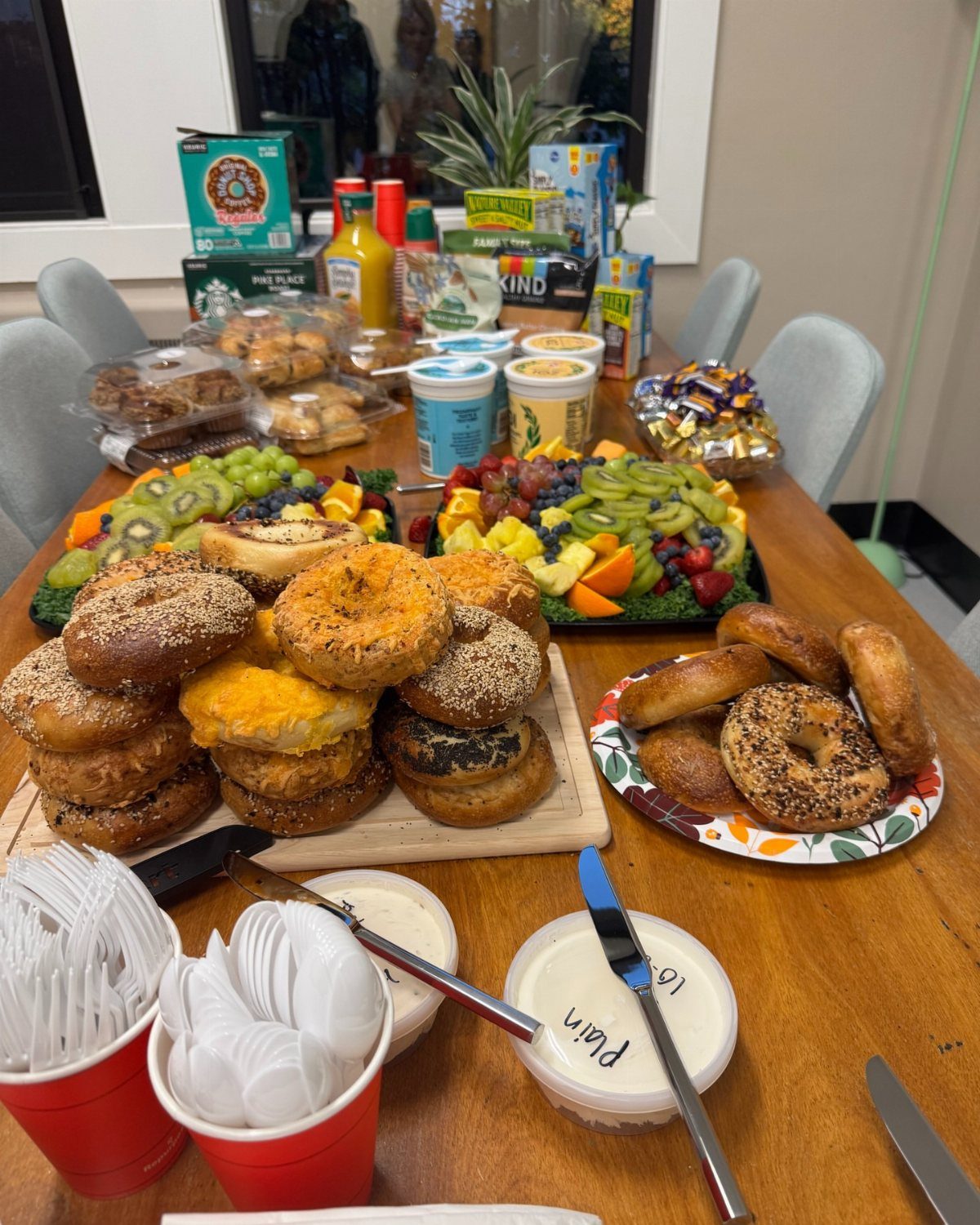 Assorted bagels and cream cheese spreads on a table with fruit platters.