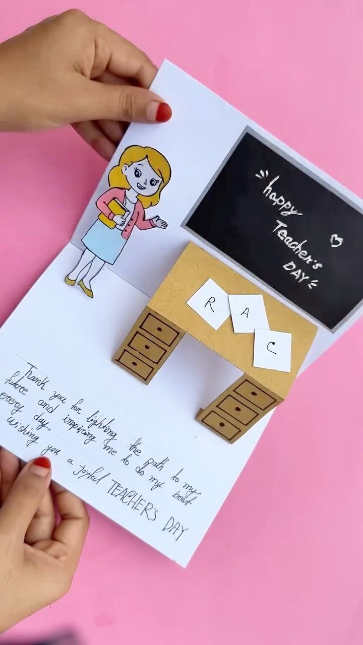Handmade pop-up teacher's day card with a cartoon teacher and small desk.