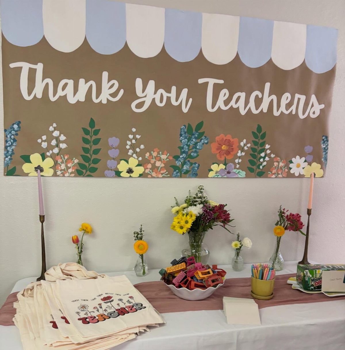 Teacher appreciation table with a Thank You Teachers banner, tote bags, and flowers.