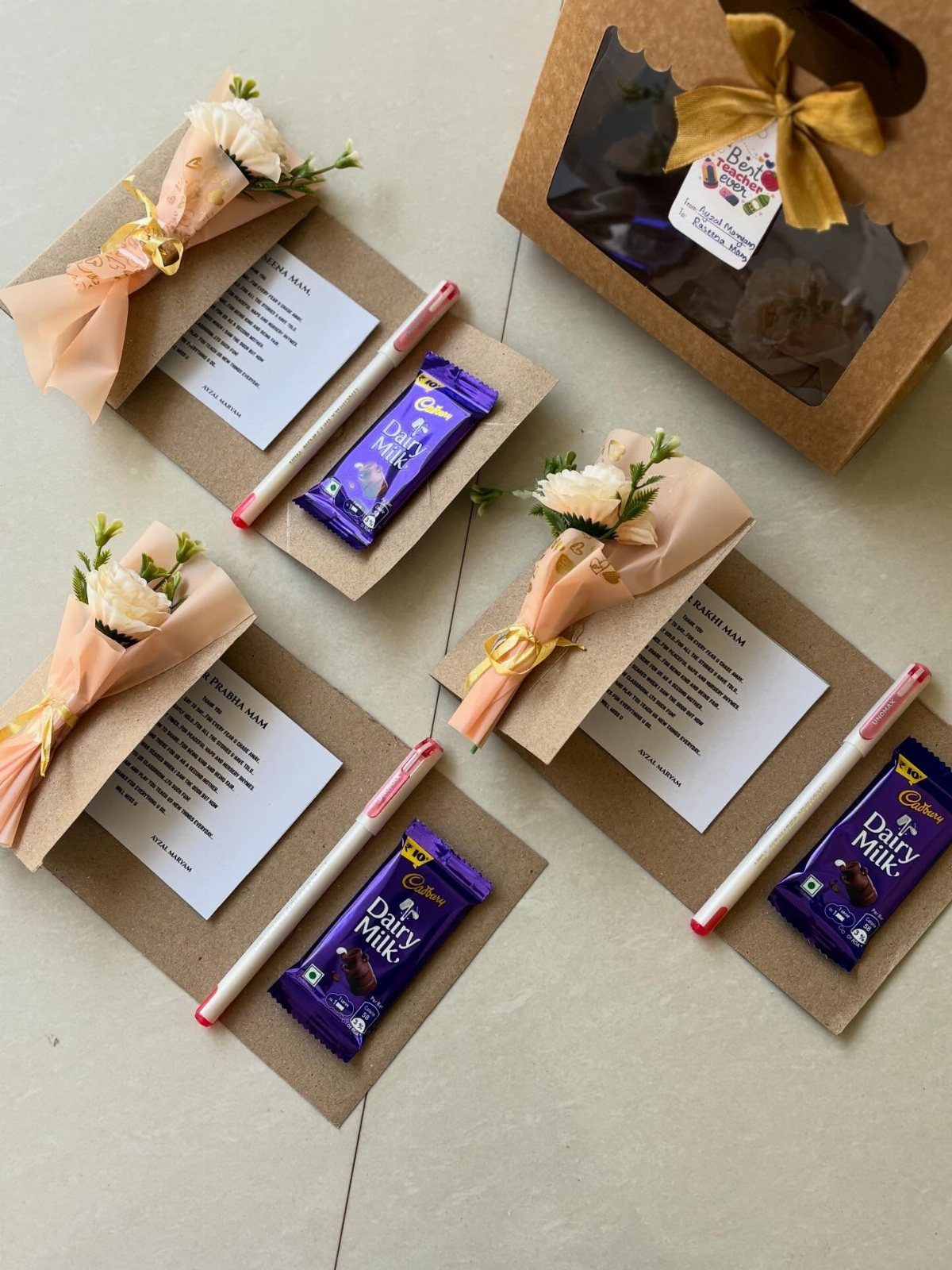 Three gift sets with chocolate bars, small flower bouquets, pens, and handwritten notes.