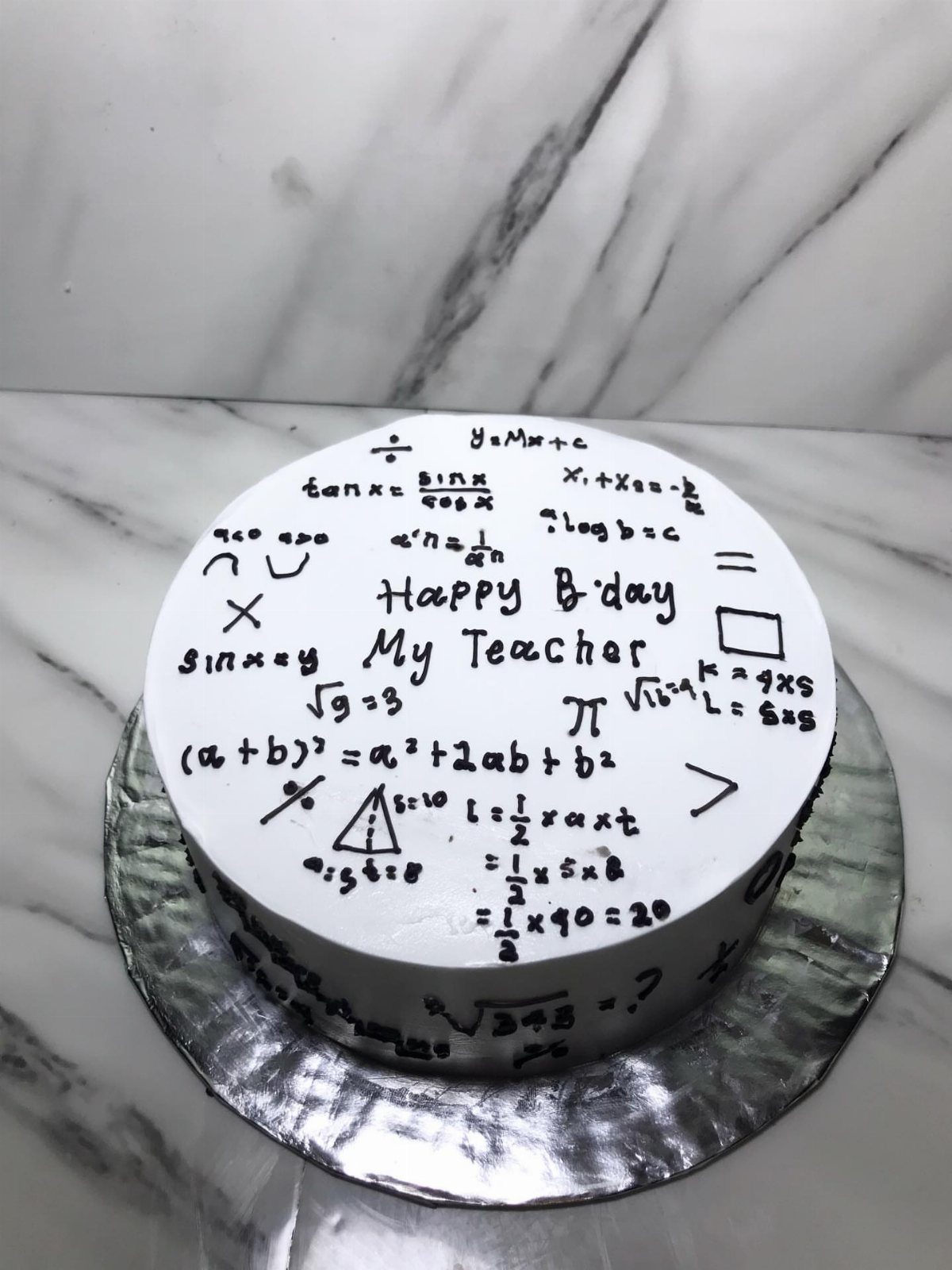 White round cake decorated with black math formulas and Happy Birthday teacher text