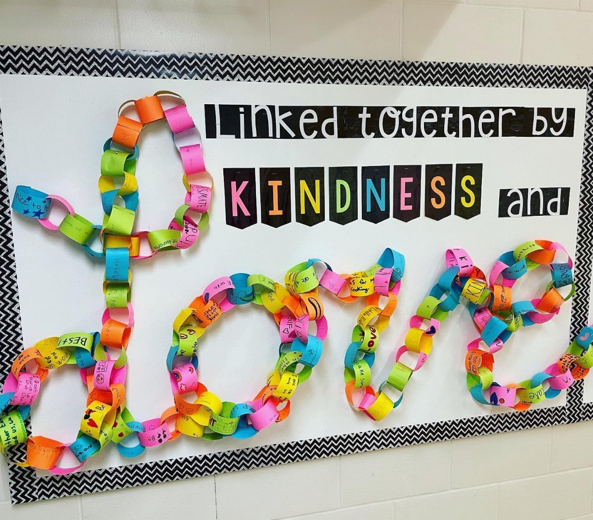 Colorful paper chain links spelling LOVE on a classroom kindness bulletin board.