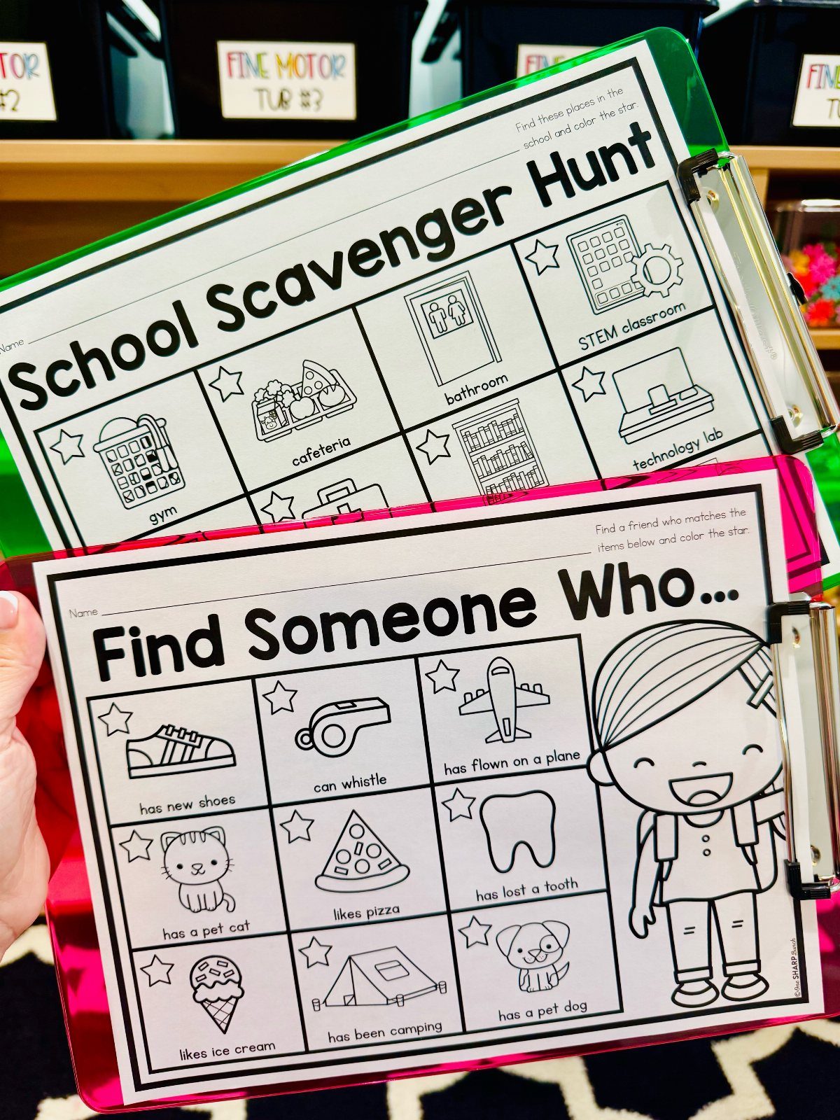Two clipboards holding a school scavenger hunt sheet and a find someone who bingo card
