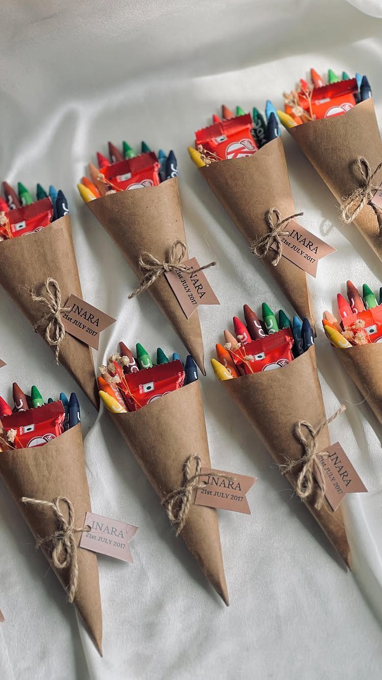 Brown paper cones filled with colorful crayons and red candies tied with twine.