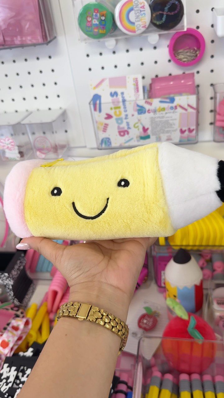 Yellow pencil shaped plush towel held in hand against a stationery background