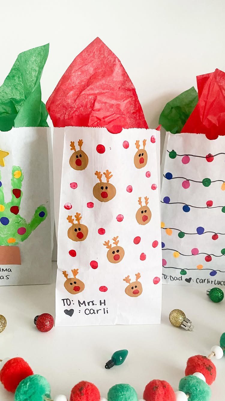 Hand-decorated white paper gift bags with reindeer and cactus drawings for teachers.